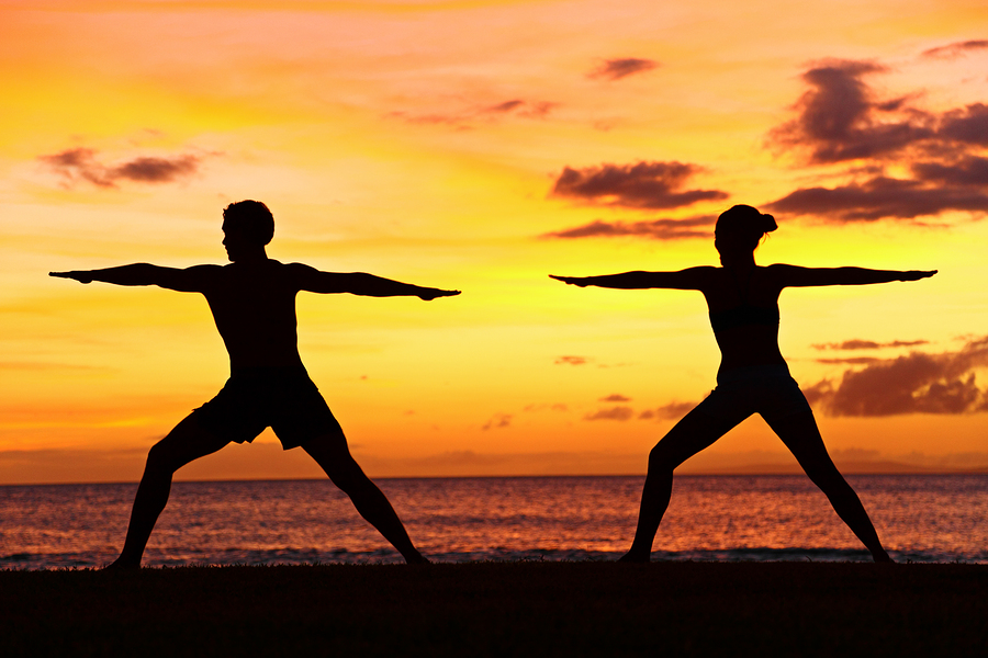 Yoga people training and meditating in warrior pose outside by b